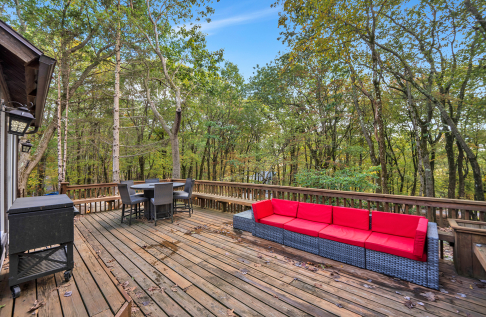 A deck with a table and a couch in the woods AI-generated content may be incorrect., Picture