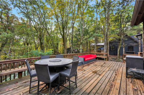 A deck with a table and chairs in the woods AI-generated content may be incorrect., Picture